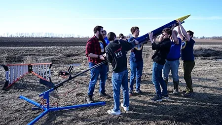 Small group of students and professors setting up rocket