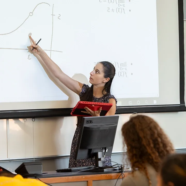 Professor at the front of a classroom teaching calculus equations.